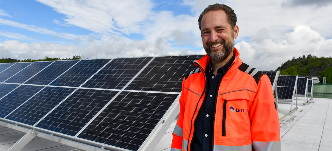 Mann som smiler foran takmonterte solceller